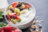 A white bowl filled with yogurt, granola, strawberries, kiwi slices, and blackberries, with a small bowl of strawberries in the foreground.